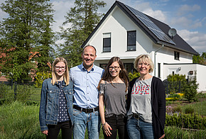 Familie Klau vor ihrem Eigenheim mit Photovoltaik-Anlage auf dem Dach.