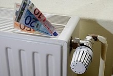 Geldscheine in einem weißen Heizkörper, rechts daneben ein Thermostat